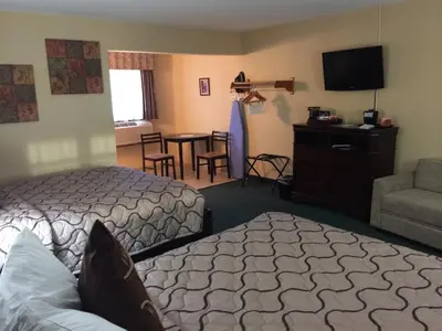 a hotel room with two beds and a chair and a table at Pacer Inn & Suites Motel in Delaware