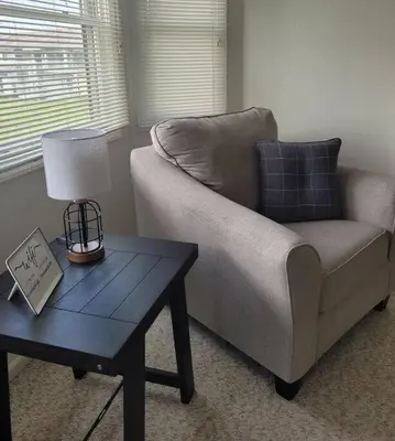 a living room with a couch and a table with a lamp at Sunnie Days condo in Oak Harbor on Lake Erie! in Sand Beach