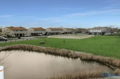 a body of water in front of a field with houses at Sunnie Days condo in Oak Harbor on Lake Erie! in Sand Beach