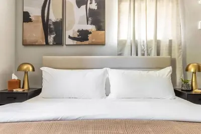 a bedroom with a bed with white sheets and two lamps at Westlake Harmony in Westlake