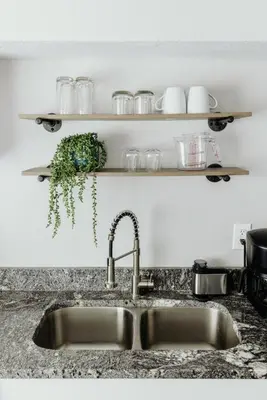 a kitchen sink with a faucet and a shelf with glasses at Westlake Apartment in Westlake