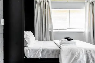 a bedroom with a bed with white sheets and a window at Westlake Apartment in Westlake