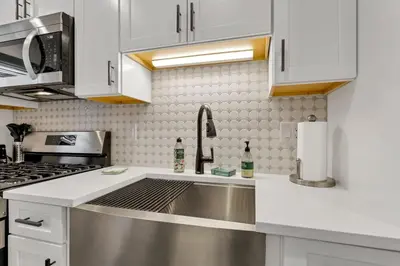 a kitchen with white cabinets and a stainless steel sink at The Worthington - 3 BR 2 5 Bath and Parking in Columbus