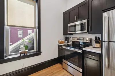 a kitchen with black cabinets and a window at Sleek Millersburg Apartment in Downtown! in Millersburg