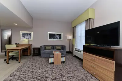 a hotel room with a flat screen tv and a couch at Homewood Suites by Hilton Cincinnati/Mason in Mason