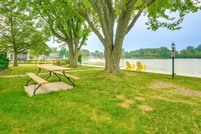 a picnic table and bench under a tree next to the water at Lakefront St Marys Getaway with Boat Dock and Fire Pit in Southmoor Shores