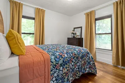 a bedroom with a bed with a colorful blanket and windows at The Bird Cage in Xenia