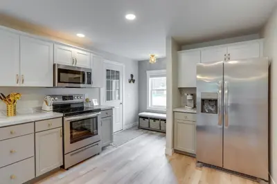 a kitchen with white cabinets and a stainless steel refrigerator at Port Clinton Vacation Rental with Boat Dock and Grill! in Port Clinton