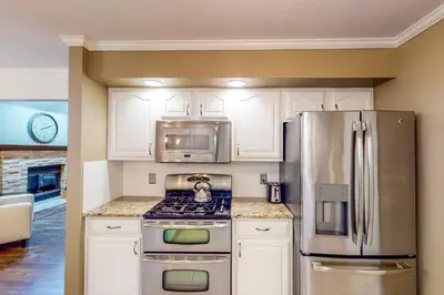 a kitchen with white cabinets and a stainless steel refrigerator at Dog-Friendly Yard! Family Retreat in Fort Wayne in Sunnybrook Acres