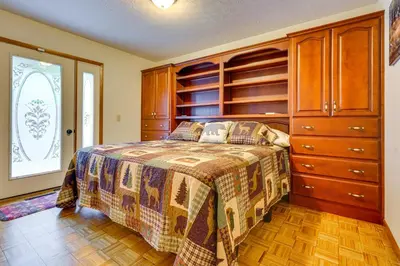 a bedroom with a bed and wooden cabinets at Cabin with Deck about 3 Mi to Apple Valley Lake! in Mount Vernon