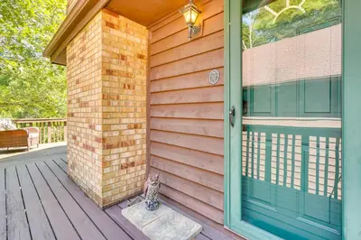 a cat sitting on the front porch of a house at Cabin with Deck about 3 Mi to Apple Valley Lake! in Mount Vernon