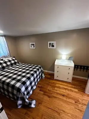 a bedroom with a bed and a dresser with a lamp at Entire Home in Cambridge City in Cambridge City