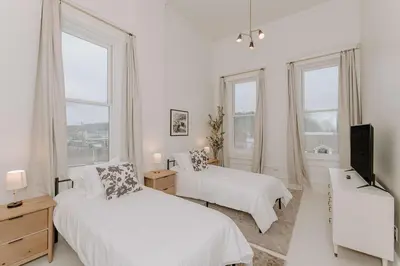 a white bedroom with two beds and a television at East Main Lofts in Madison