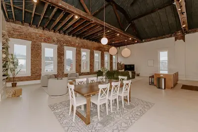 a dining room with a table and white chairs at East Main Lofts in Madison