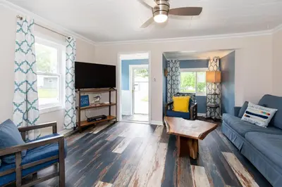 a living room with a blue couch and a tv at Explorers Cottage at Rye Beach in Huron