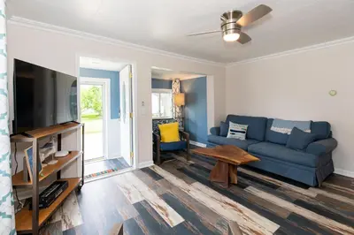 a living room with a blue couch and a tv at Explorers Cottage at Rye Beach in Huron