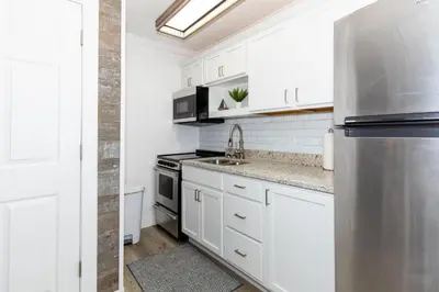 a kitchen with white cabinets and a stainless steel refrigerator at Downtown Waterfront Escape in Sandusky