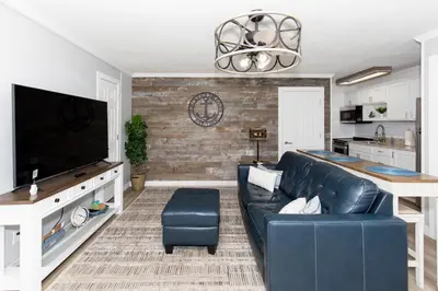 a living room with a black leather couch and a tv at Downtown Waterfront Escape in Sandusky