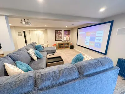 a living room with a large blue couch and a large screen at Lakefront 5 Bedroom Vacation Home - Sleeps 12! in Vermilion
