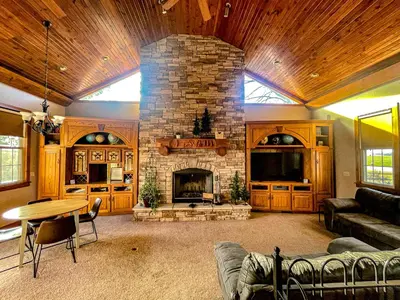 a living room with a stone fireplace in a house at Charming School House with Large Pool in Huron