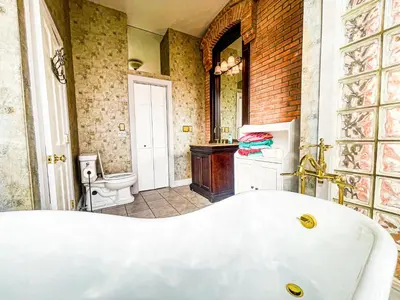 a bathroom with a white tub and a toilet at Charming School House with Large Pool in Huron