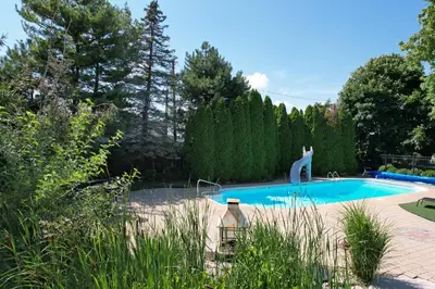 a swimming pool in a garden with a statue next to it at Charming School House with Large Pool in Huron