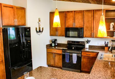 a kitchen with wooden cabinets and black appliances at Newly Renovated! Old Homestead Beach Home in Huron