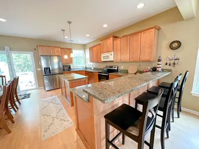 a kitchen with wooden cabinets and a kitchen island with bar stools at 5 Bedroom Home in Old Homestead II in Huron