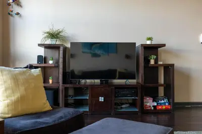 a living room with a television in a wooden entertainment center at Marlin at the Lake - Downtown Sandusky in Sandusky