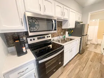 a kitchen with white cabinets and a stove and a microwave at Side-by-Side Family Apartments - Sleeps 15 Total in Huron