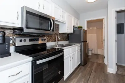 a kitchen with white cabinets and black appliances at Side-by-Side Family Apartments - Sleeps 15 Total in Huron