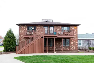 a brick house with a deck and balcony at Side-by-Side Family Apartments - Sleeps 15 Total in Huron