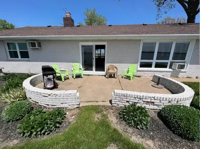 a house with a patio with green chairs in it at 4 Bedroom Lakefront Home with Private Beach on Cedar Point Chaussee in Sandusky