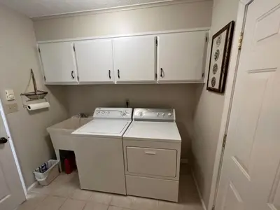 a kitchen with white cabinets and a washer and dryer at 4 Bedroom Lakefront Home with Private Beach on Cedar Point Chaussee in Sandusky