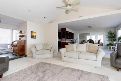 a living room with two white couches and a ceiling fan at 4 Bedroom Lakefront Home with Private Beach on Cedar Point Chaussee in Sandusky