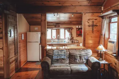 a living room with a couch and a kitchen at Great Frontier Cabin at American Heartland Cabins in Rockbridge
