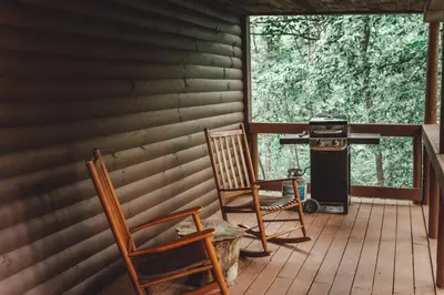 two chairs and a grill on the porch of a cabin at Great Frontier Cabin at American Heartland Cabins in Rockbridge