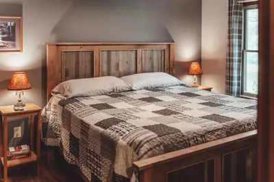 a bedroom with a large bed with a checkered blanket at Patriot Cottage at American Heartland Cabins in Rockbridge