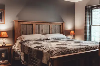 a bedroom with a wooden bed with two lamps at Patriot Cottage at American Heartland Cabins in Rockbridge