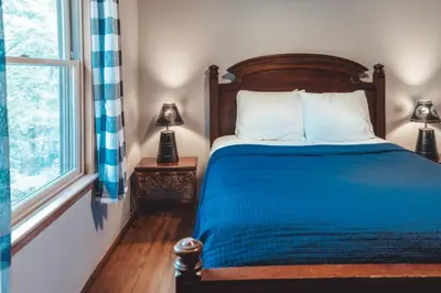 a bedroom with a bed with blue sheets and a window at Patriot Cottage at American Heartland Cabins in Rockbridge
