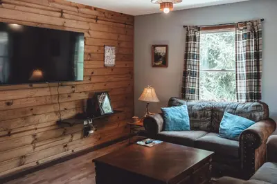 a living room with a couch and a flat screen tv at Patriot Cottage at American Heartland Cabins in Rockbridge