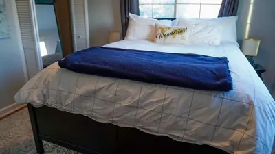 a bed with a blue blanket on top of it at Winter Retreat 2BR, Minutes from OSU & Downtown in Columbus