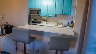 a kitchen with blue cabinets and two chairs at a counter at Winter Retreat 2BR, Minutes from OSU & Downtown in Columbus