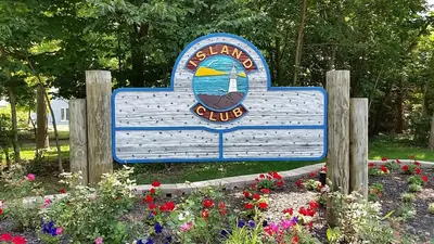a sign in the middle of a garden with flowers at Island Club Rentals in Put-in-Bay