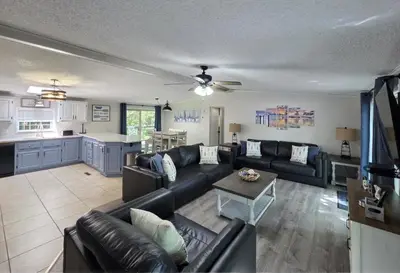 a living room with a black couch and a kitchen at Island Club Rentals in Put-in-Bay