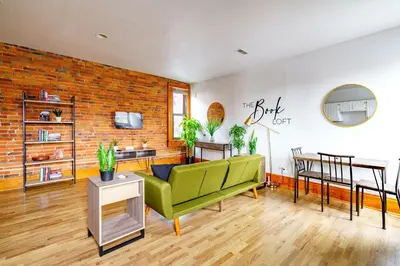 a living room with a green couch and a brick wall at Jungle House Columbus Downtown Free Parking Sleeps 8 - Walk to Convention Center & Nationwide Arena - 1BR Short North Luxury Home - Over 5,800 Five Star Stays in Columbus