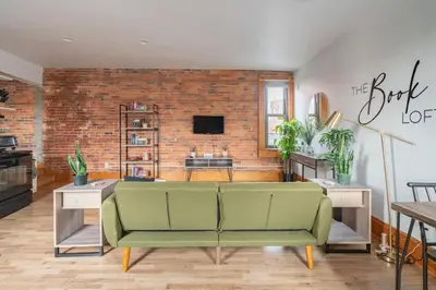 a living room with a green couch and a brick wall at Jungle House Columbus Downtown Free Parking Sleeps 8 - Walk to Convention Center & Nationwide Arena - 1BR Short North Luxury Home - Over 5,800 Five Star Stays in Columbus