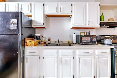 a kitchen with white cabinets and a stainless steel refrigerator at Jungle House Columbus Downtown Free Parking Sleeps 8 - Walk to Convention Center & Nationwide Arena - 1BR Short North Luxury Home - Over 5,800 Five Star Stays in Columbus