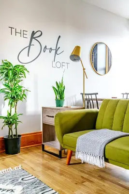 a green couch in a living room with plants at Jungle House Columbus Downtown Free Parking Sleeps 8 - Walk to Convention Center & Nationwide Arena - 1BR Short North Luxury Home - Over 5,800 Five Star Stays in Columbus