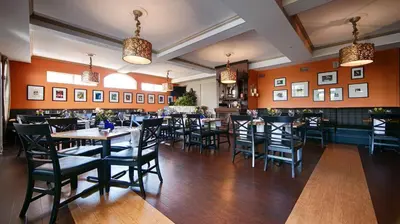 a dining room with tables and chairs and orange walls at Best Western Plus Mentor-Cleveland Northeast in Mentor